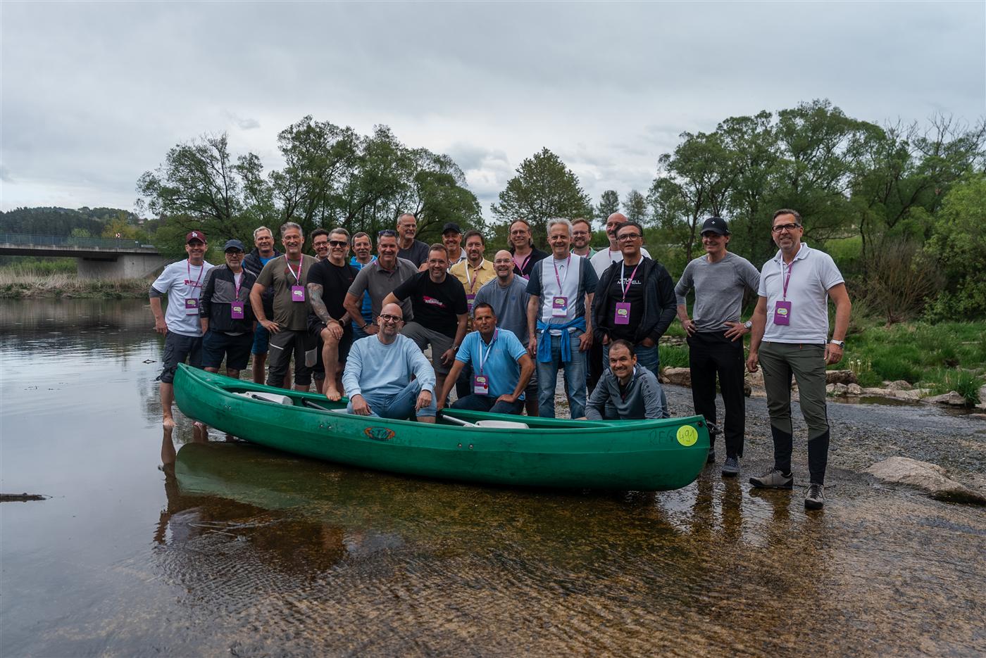 Gruppenfoto der Handelsvertreter am Fluss, mit Kanu und Namensschildern